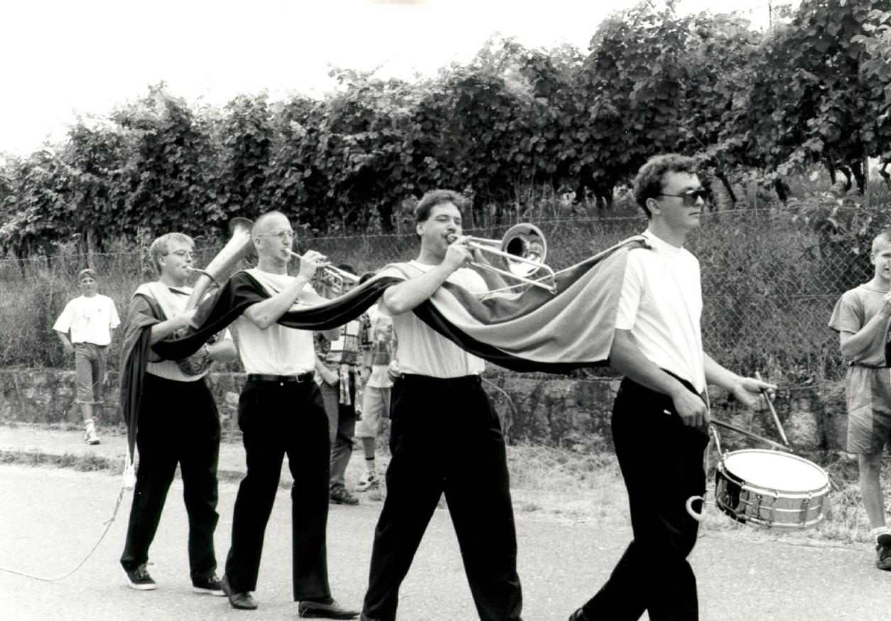4 Musiker laufen in einer Reihe und tragen eine Fahne.
