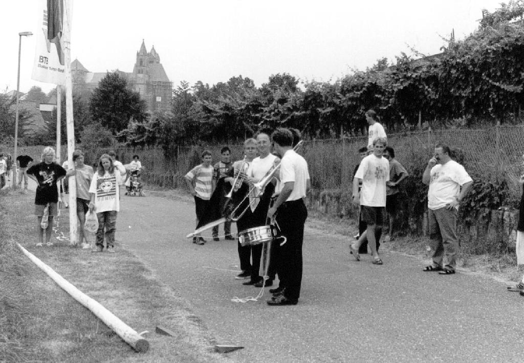 4 Musiker laufen in einer Reihe und tragen eine Fahne.